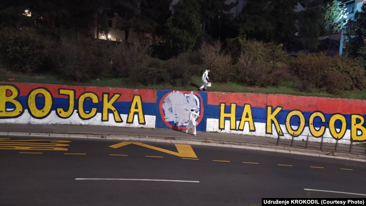 Aktivistët duke fshirë grafitin “Kur ushtria të kthehet në Kosovë” në një rrugë në Beograd. Maj 2026.