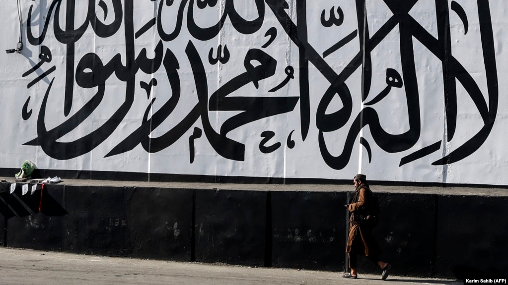  A man walks past a wall mural depicting the Taliban flag in Kabul.