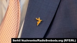 Нагрудний значок у вигляді факела, який є символом логотипу Радіо Вільна Європа / Радіо Свобода