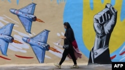 Жінка проходить повз антиамериканський та антиизраїльський мурал у Тегерані, 8 квітня 2026 року