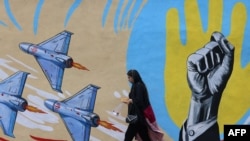 A woman walks past an anti-US, anti-Israel mural in Tehran on April 8.