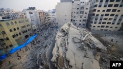 Egy izraeli bombatalálatban megsemmisült épület romjait járják körbe az emberek Gázában. 2023. október 8. 