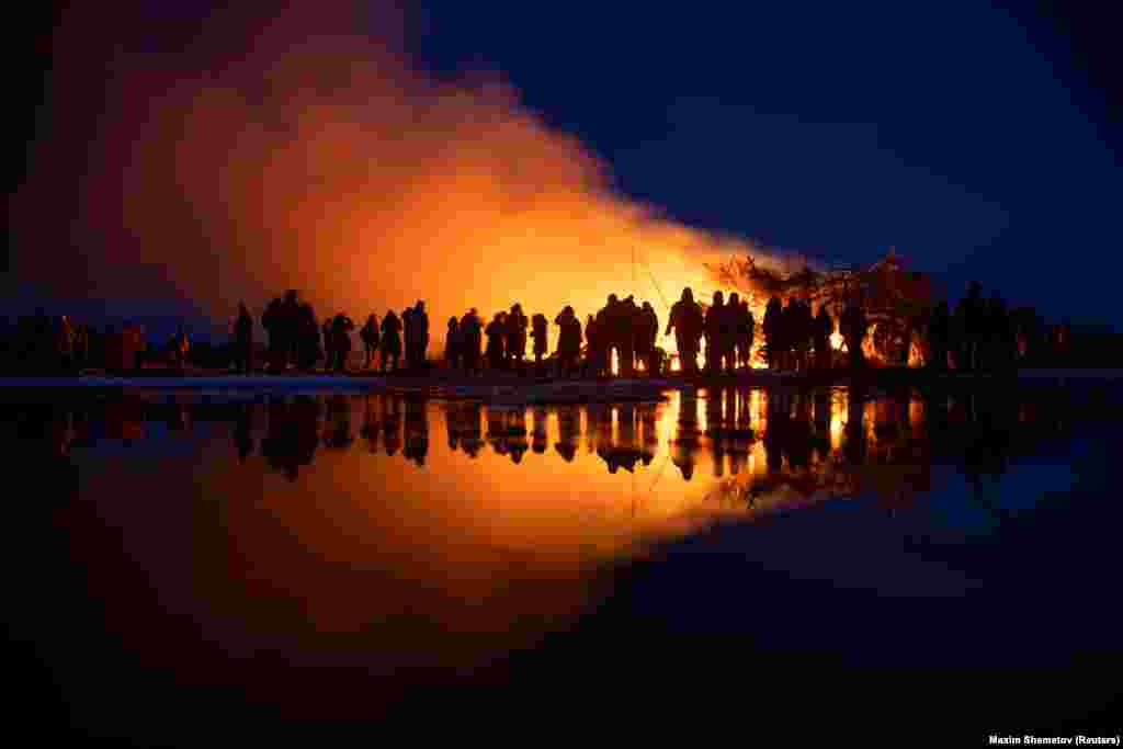 People watch a burning installation called Vaccination Tower during celebrations of Maslenitsa in Russia&#39;s Kaluga region.