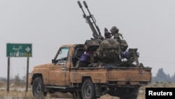 A rebel fighter sits on the back of a vehicle in the countryside of Homs Province amid a lightning offensive by forces opposed to authoritarian Syrian President Bashar al-Assad on December 7. 