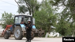 A Kazakh police officer blocks a street near the site of an exchange between Kazakh security forces and suspected militants linked to deadly attacks this week on a national guard base and several firearms shops, in Aqtobe, on June 10.