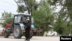 A Kazakh police officer blocks a street near the site of a fire exchange between Kazakh security forces and suspected militants linked to deadly attacks on a national guard base and several firearms shops in the city of Aqtobe in June.