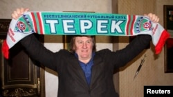 Actor Gerard Depardieu holds up a scarf of Terek Grozny soccer club as he poses for a picture during a visit to the Akhmat-Arena sports stadium in Grozny in February 2013.