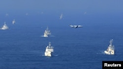 Chinese ocean surveillance and fishery patrol ships and a Japanese coast guard patrol ship (right) sail about 15 kilometers west of a group of disputed islands in the East China Sea in mid-September.