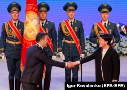 Избранный президент Кыргызстана Садыр Жапаров и председатель Центральной избирательной комиссии (ЦИК) Нуржан Шайлдабекова обмениваются рукопожатием во время церемонии инаугурации в Бишкеке, 28 января 2021 года.