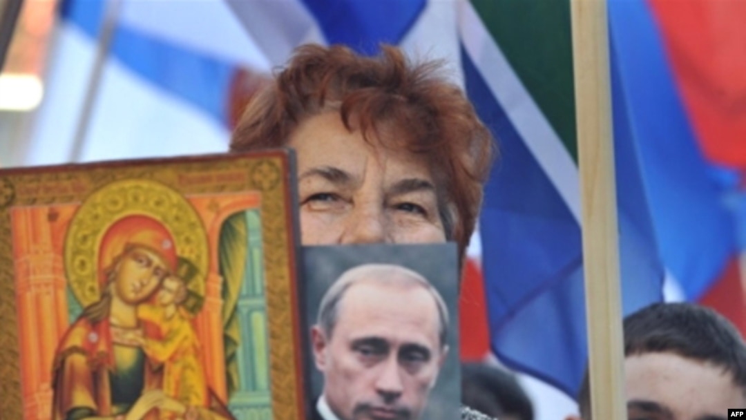 A Kosovo Serbian woman holds a religious icon and portrait of Russian leader Vladimir Putin during a protest in Mitrovica in February 2008.