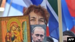 A Kosovo Serbian woman holds a religious icon and portrait of Russian leader Vladimir Putin during a protest in Mitrovica in February 2008.