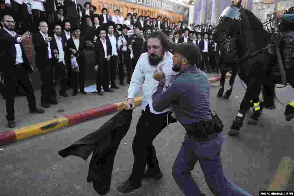 Israeli security forces carry away an ultra-Orthodox Jewish demonstrator as they disperse a protest against Israeli Army conscription in Bnei Brak, a city near Tel Aviv. (AFP/Ahmad Gharabli)