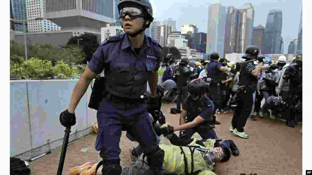 Rendőrök és tüntetők összecsapása 2014. december 1-jén Hongkongban, majd ugyanez az utcakép egy 2015. szeptember 26-i felvételen.&nbsp;A tüntetők elfogadták és betartották az erőszakmentes polgári engedetlenség elvét, és hajlandók voltak vállalni az ebből fakadó jogi felelősséget. Gyakran táblákkal kértek elnézést az okozott kellemetlenségekért