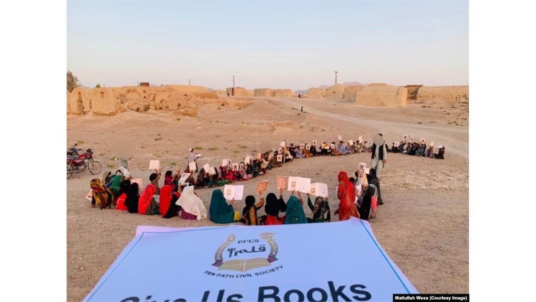 Un grup de copii primește cărți și articole de papetărie în timpul unei întâlniri școlare, în provincia Kandahar. Fotografie realizată la data de 1 august 2021.