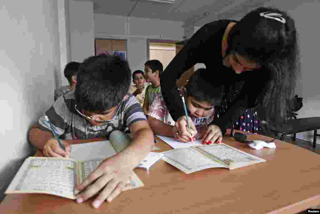 Schoolchildren belonging to the Afghan community in Moscow learn Dari and Pashto with their teacher.