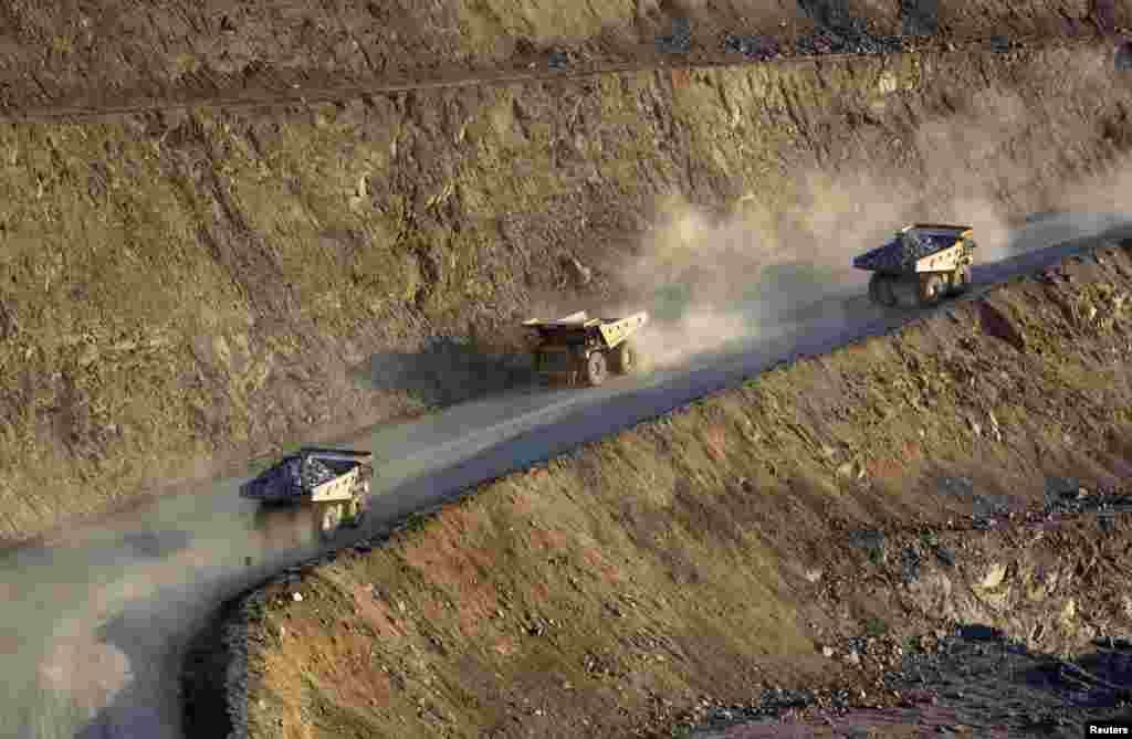 Near the extraction plant, trucks drive along a road at the Altyntau open pit gold mine.