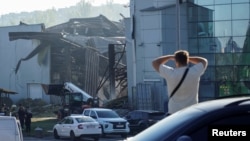 A resident looks on as rescuers work at the site of a shopping center hit by a Russian drone attack the day before in the Ukrainian city of Kryviy Rih, on August 22.