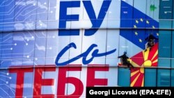 Работници поставуваат постер на седиштето на Европската Унија во Скопје 