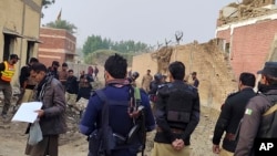 Security officials examine damage at the site of a bombing at a police station on the outskirts of Dera Ismail Khan, Pakistan, on December 12, 2023.