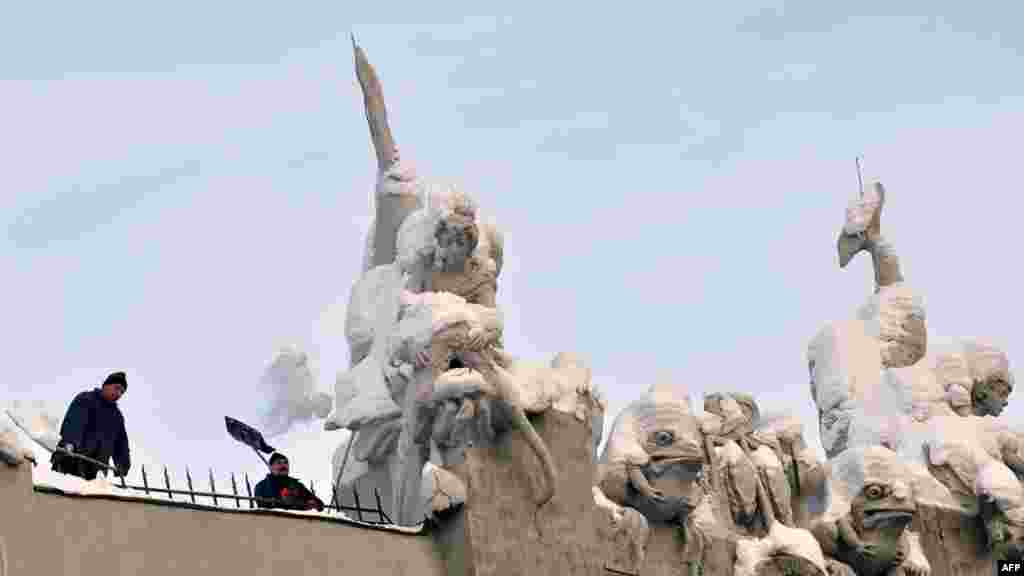 Workers clean snow from sculptures adorning the roof of the Chimera House by architect Vladyslav Horodetskiy in the Ukrainian capital, Kyiv.