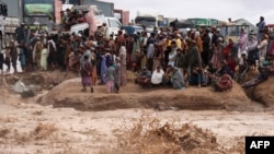 مسافران منتظر عبور از یک جادۀ سیل‌زده در ولسوالی زاول ولایت هرات