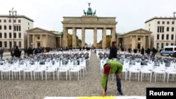 Un bărbat așează o piatră într-un gest comemorativ pe un panou, lângă fotografiile victimelor atacului Hamas din urmă cu doi ani. Poarta Brandenburg din Berlin, Germania, 7 octombrie 2025.