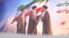 A portrait seen hanging in Tehran on March 11 shows Iran's previous Supreme Leader Ayatollah Ali Khamenei passing the flag to his son and successor, Mojtaba Khamenei.