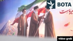 Një portret i vendosur në Teheran më 11 mars shfaq ish-udhëheqësin suprem të Iranit, Ajatollah Ali Khamenei, duke ia kaluar flamurin djalit dhe pasardhësit të tij, Mojtaba Khamenei.