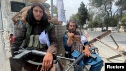 Taliban fighters sit at a checkpoint in Kabul.