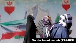 Iranke prolaze pored bilborda sa zastavom Irana, Tehran, 19. februar 2021.
