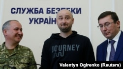 Arkady Babchenko (center) stands beside Ukrainian Prosecutor-General Yuriy Lutsenko (right) and the head of the state security service (SBU), Vasiliy Gritsak, during a news briefing in Kyiv where it was revealed that Babchenko's supposed killing was part of a sting operation.