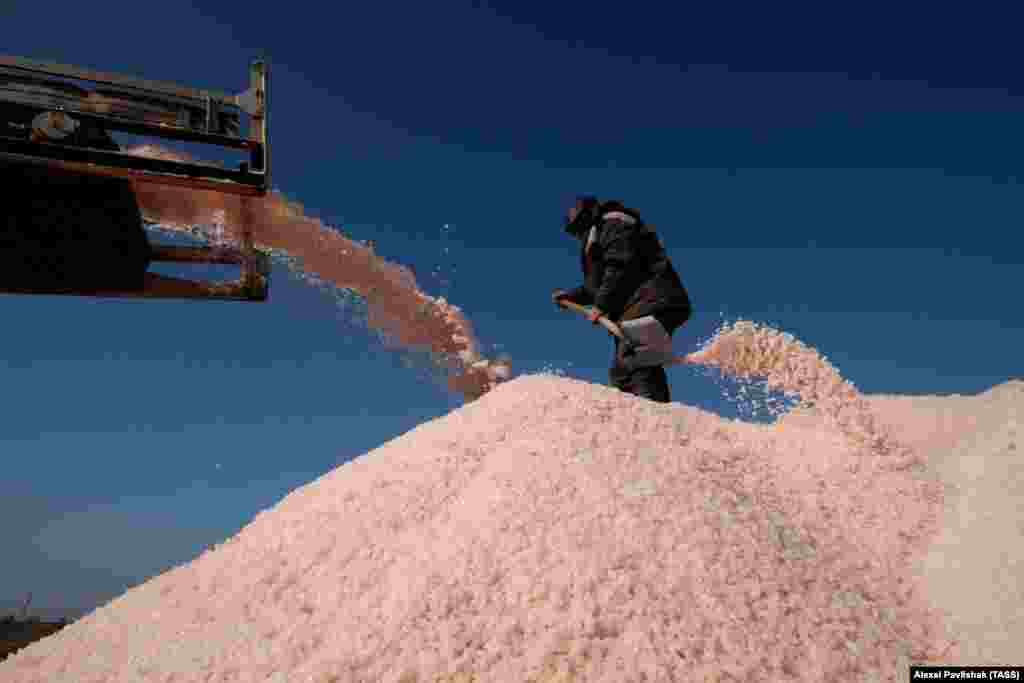 A man shovels salt at the top of a heap. The rare pink salt is exported to European countries and to Japan, where it is prized for its purported value in fighting the effects of radiation.