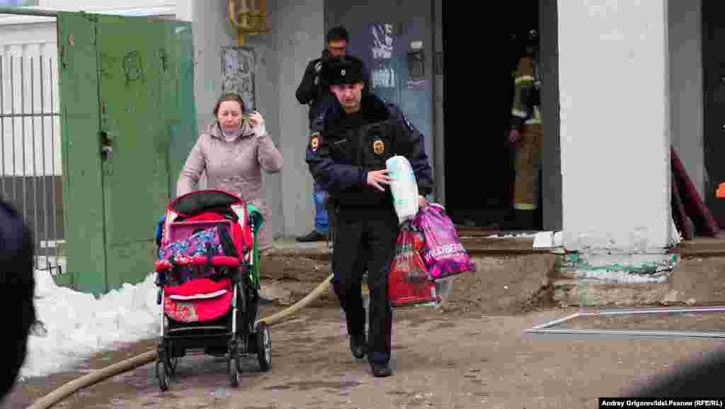 Сотрудник полиции помогает женщине выносить вещи. Судя по всему, на фото жительница одной из наиболее пострадавших от огня и воды квартир.&nbsp;