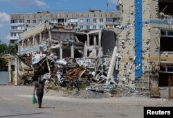 Мужчина идет мимо разрушенного здания, Мариуполь. Донецкая область, Украина, 16 августа 2023 года