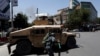 An Afghan policeman covers himself as smoke rises from the site of an attack in Kabul on July 31.