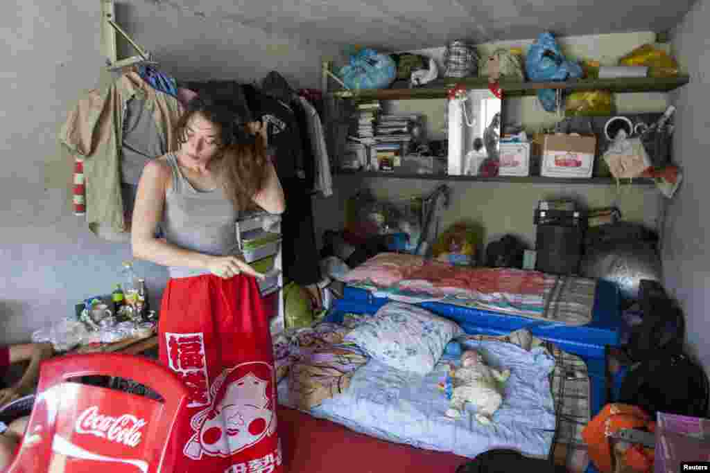 Political activist Natalia Sokol brushes her hair as Gera, the baby of fellow activist Nadezhda Tolokonnikova, lies on a mattress in the car shed that served as the home of the Voina activist group in Moscow in July 2008.