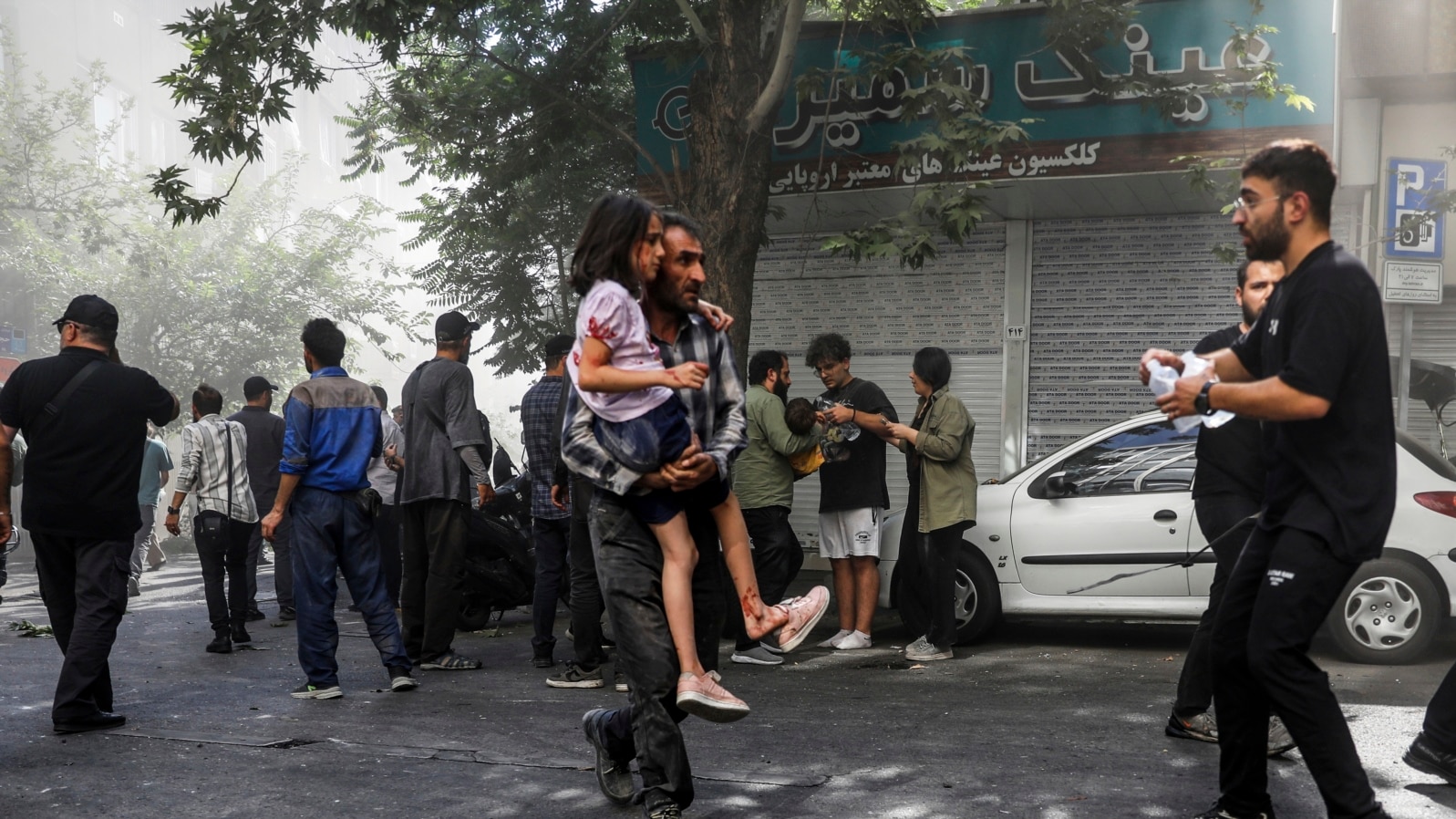 Iran, 15 iunie 2025. Un bărbat cară o fată rănită după o explozie în centrul Teheranului, care a urmat unor lovituri israeliene asupra unor ținte din Iran.
