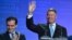 Romanian President Klaus Iohannis (right) with Prime Minister Ludovic Orban by his side waves to supporters after the first-round results are announced. 
