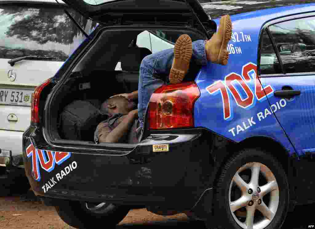 Un reporter sud-african odihnindu-se &icirc;n așteptarea lui Oscar Pistorius la o secție de poliție din Pretoria, 25 februarie.