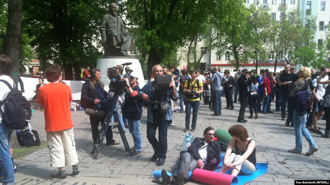 Russian protesters rest on camping mats in front of the statue of Abai in Moscow.