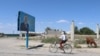 Велосипедист едет мимо баннера с изображением бывшего президента Казахстана Нурсултана Назарбаева. Село Шорнак, Сауранский район, Туркестанская область, 30 июня 2021 года 