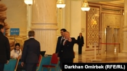 Экс-президент Нурсултан Назарбаев подходит к членам участковой комиссии в Астане. 15 марта 2016 года