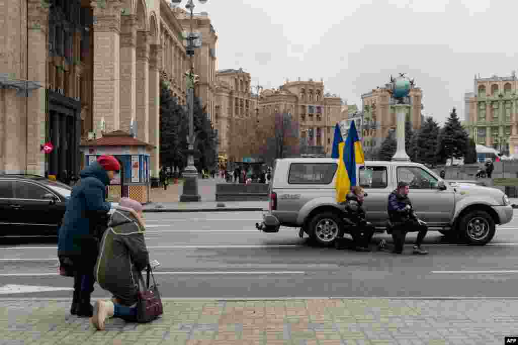 People kneel to honor a fallen Ukrainian soldier during a funeral procession on Kyiv&#39;s Independence Square.&nbsp;