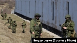 Российские военные в форме без опознавательных знаков перед территорией украинской военной базы в Крыму в один из дней до аннексии полуострова.