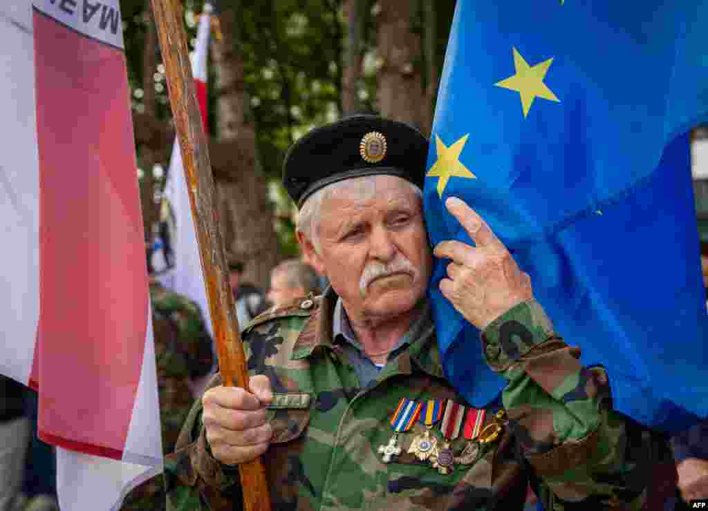 Un veteran al armatei moldovenești atinge drapelul UE în timpul unei ceremonii în cinstea militarilor care au luptat în cel de-al Doilea Război Mondial, la care au participat și autoritățile centrale ale Republicii Moldova, în cadrul ceremoniei Zilei Victoriei celui de-al Doilea Război Mondial și Zilei Europei, la Chișinău, pe 9 mai 2024.&nbsp; &nbsp;