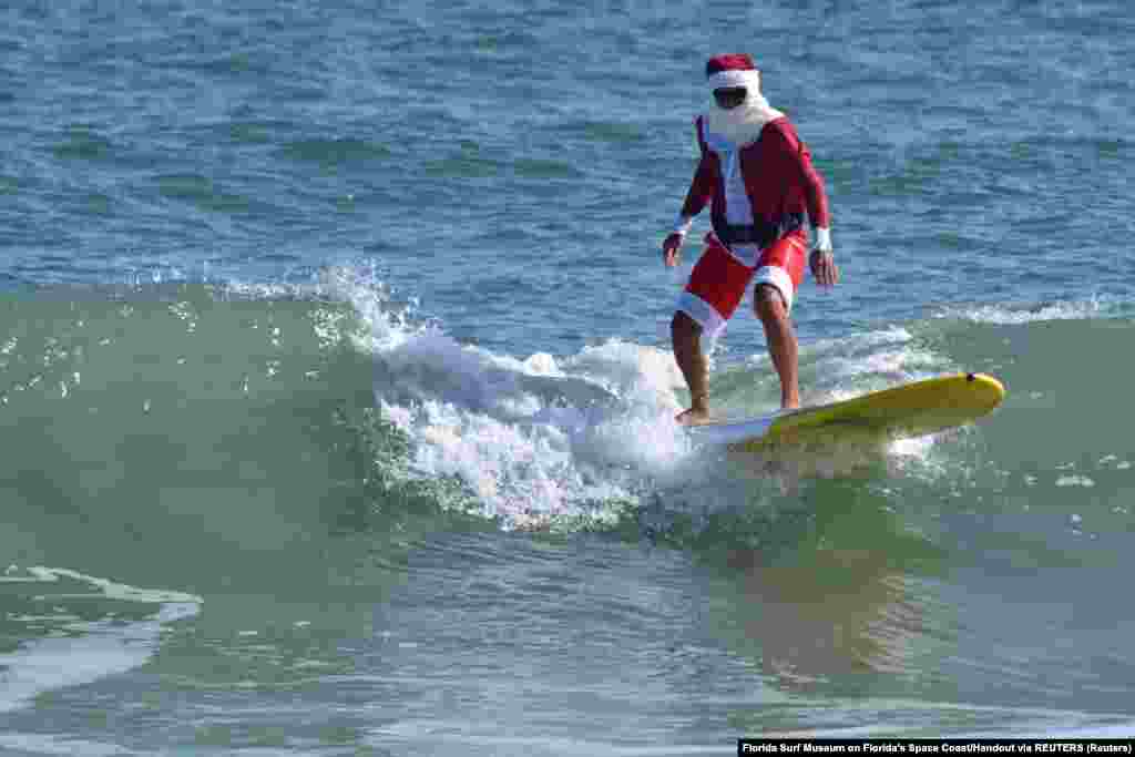 Mikulásruhába öltözve szörfözik egy férfi Florida egyik strandján december 23-án.