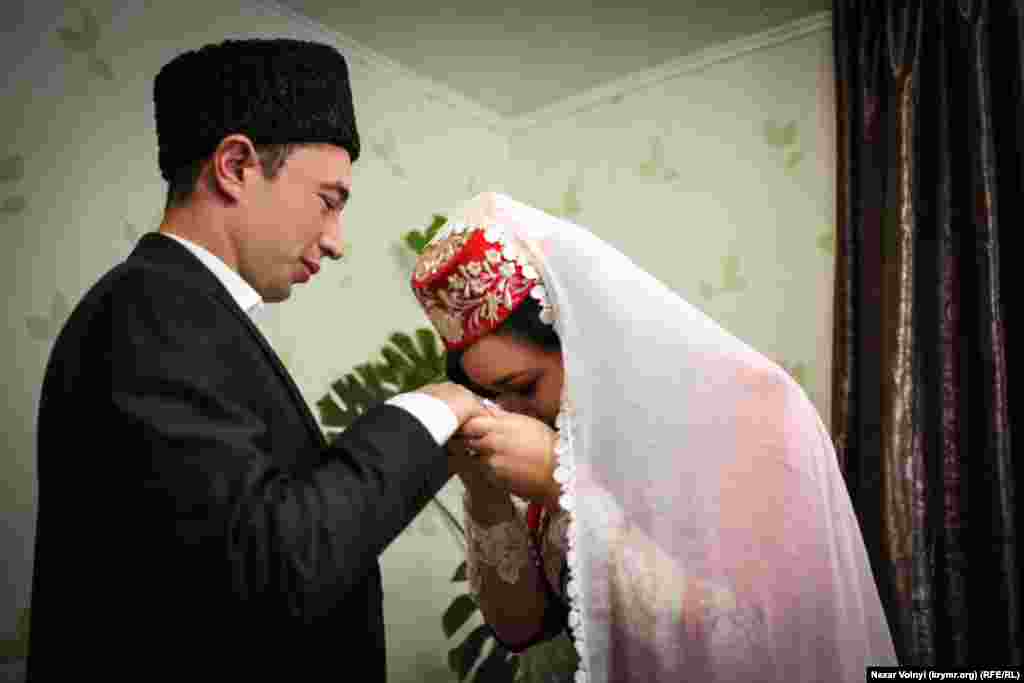 The bride kisses her husband&#39;s hand, a traditional sign of respect given after marriage vows have been exchanged.&nbsp;