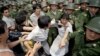 file -- A young woman is caught between civilians and Chinese soldiers, who were trying to remove her from an assembly near the Great Hall of the People in Beijing, June 3, 1989. 