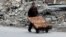 A man selling pastries walks past the rubble of damaged buildings in the rebel held al-Shaar neighborhood of Aleppo on February 10.