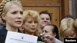 Opposition leader Yulia Tymoshenko shows reporters a summon for a May 17 meeting with investigators, as she leaves the general prosecutor's office in Kyiv on May 12.